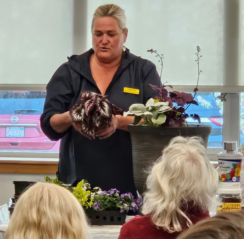 Jenna Porter is holding a plant as she speaks at McAuliffe Library